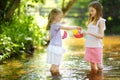 Two little sisters playing with paper boats by a river on warm and sunny summer day. Children having fun by the water. Royalty Free Stock Photo