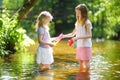 Two little sisters playing with paper boats by a river on warm and sunny summer day. Children having fun by the water. Royalty Free Stock Photo