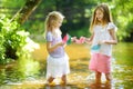 Two little sisters playing with paper boats by a river on warm and sunny summer day. Children having fun by the water. Royalty Free Stock Photo