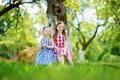 Two little sisters sitting on a haystack in apple tree garden Royalty Free Stock Photo