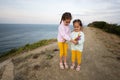 Two little sisters tanding on the edge of a cliff with wildflowers bouquet against sea Royalty Free Stock Photo