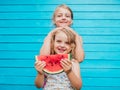 Two little sisters together with red ripe watermelon smiling