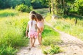 Two little sisters walking and playing on the road in countryside on a warm summer sunset. Cute little girls. Back view Royalty Free Stock Photo