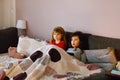 Two little sisters watching cartoons on tv in bed. Cute girls, lovely children in pajamas having fun together and Royalty Free Stock Photo