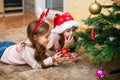 Two little sisters write the letter to Santa under the Christmas tree