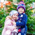 Two little smiling kids, boy and girl hugging on German Christmas market. Happy children in winter clothes with lights Royalty Free Stock Photo