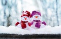 Two little snowmen the girl and the boy in caps and scarfs on snow in the winter. Background with a funny snowman Royalty Free Stock Photo