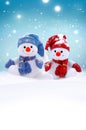 Two little snowmen the girl and the boy in caps and scarfs on snow in the winter. Background with a funny snowman Royalty Free Stock Photo