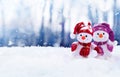Two little snowmen the girl and the boy in caps and scarfs on snow in the winter. Background with a funny snowman Royalty Free Stock Photo