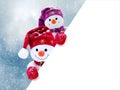 Two little snowmen the girl and the boy in caps and scarfs on snow in the winter. Background with a funny snowman. Christmas card Royalty Free Stock Photo