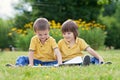 Two little sweet boys, brothers, reading a book in the park