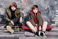 Two little twin boys in casual clothes sitting on skateboard in studio. Teen and kids fashion concept. Royalty Free Stock Photo