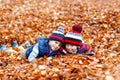 Two little kid boys lying in autumn leaves, in park. Royalty Free Stock Photo