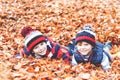 Two little twin boys lying in autumn leaves in colorful clothing. Happy siblings kids having fun in autumn forest or Royalty Free Stock Photo