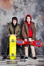 Two little twin boys in casual clothes with skateboards in studio. Teen and kids fashion concept.