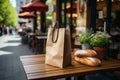 Two loaves of freshly baked wheat bread and a craft paper bag lie on the table of a street cafe, bakery and Royalty Free Stock Photo