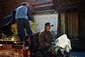 two local villager transports a tibetan buddhist shrine on a motorbike in front of a typical decorated gate