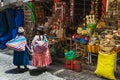 Two local woman wearing traditional clothing in front of a store in a street of the city of La Paz, in Bolivia