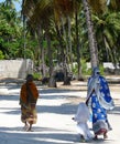 Two local women and child walking by palm trees, Jambiani, Zanzibar Royalty Free Stock Photo