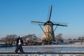 Two locals on a frozen windmill canal pathway at sunrise moment Royalty Free Stock Photo