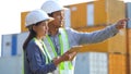 Two logistic staff discussing while checking and control loading containers box from cargo.