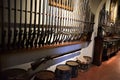 Two long racks attached to a wall support dozens of ancient rifles of various sizes.