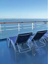 Two lounge chairs on a cruise ship deck overlooking the ocean and a beautiful blue sky Royalty Free Stock Photo