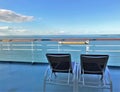 Two lounge chairs on a cruise ship deck overlooking the ocean and a beautiful blue sky Royalty Free Stock Photo