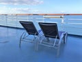 Two lounge chairs on a cruise ship deck overlooking the ocean and a beautiful blue sky Royalty Free Stock Photo