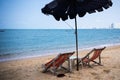 Two loungers and an umbrella on the blue sea on the beach of Pattaya, Thailand. back view.