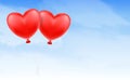 Two love heart balloon floating in blue sky