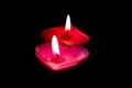 Two love heart shaped candles on a black background