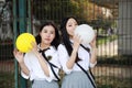 Two lovely Asian Chinese pretty girls wear student suit in school best friends smile laugh blow balloon in nature Royalty Free Stock Photo