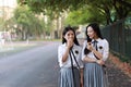 Two lovely Asian Chinese pretty girls wear student suit in school best friends smile laugh eating snack and biscuit in nature Royalty Free Stock Photo