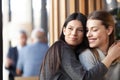 Two lovely girls hugging in a cafe and looking outside the window