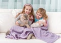 Two lovely little girls embracing on sofa Royalty Free Stock Photo