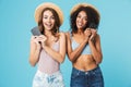 Two lovely multiethnic women 20s wearing straw hats smiling and Royalty Free Stock Photo