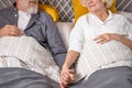 two lovely senior man and woman lie on bed together looking at each other with love, holding hands together Royalty Free Stock Photo