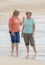 Two lovely senior mature retired women on their 60s having fun enjoying together happy walking on the beach smiling playful Royalty Free Stock Photo