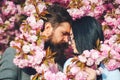 Two lovers are hugging and kissing outdoors. Happy Valentine`s Day. Young romantic couple among pink sakura flowers. Love. Spring Royalty Free Stock Photo