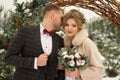 Two lovers, a man and a woman, a wedding in winter. bride and groom love. against the backdrop of decor and trees, snow. holding a Royalty Free Stock Photo