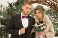 Two lovers, a man and a woman, a wedding in winter. bride and groom love. against the backdrop of decor and trees, snow. holding a Royalty Free Stock Photo