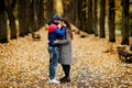 Two lovers are standing on an alley in an autumn park and hugging each other. Autumn, love, a romantic date Royalty Free Stock Photo