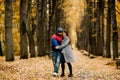 Two lovers walk along an alley in an autumn park and hug each other. Autumn, love, a romantic date Royalty Free Stock Photo