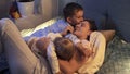 Two loving boys in pajamas hugging and kissing mother lying in bed at night. Family having time together, parenting, happy Royalty Free Stock Photo