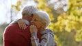 Two loving grey-haired people hugging outdoor in autumn nature
