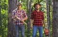 Two lumberjacks with chainsaw and axe. Male lumberjack in the forest. Woodcutter with axe and lumberjack with chainsaw.