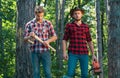 Two lumberjacks with chainsaw and axe. Male lumberjack in the forest. Woodcutter with axe and lumberjack with chainsaw.