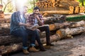 two lumberjacks sitting on logs with axe and using digital tablet Royalty Free Stock Photo
