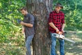 Two lumberjacks woodcutters with chainsaw and axe. Forest workers.